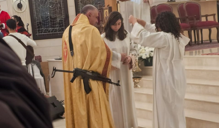 كاهن يحمل سلاحًا في قداس الميلاد